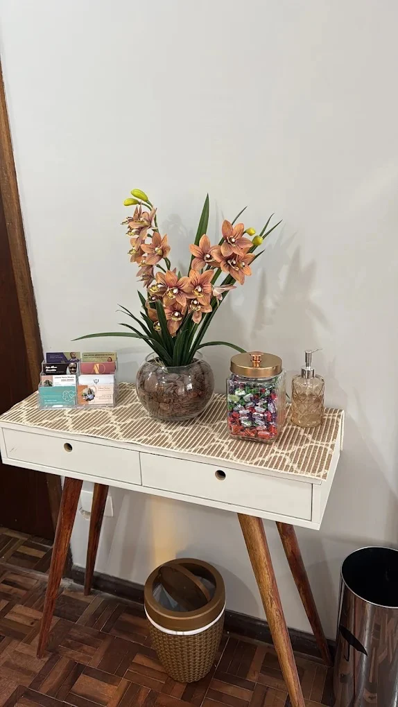 Detalhe do consultório: mesa com orquídea, cartões e objetos de acolhimento